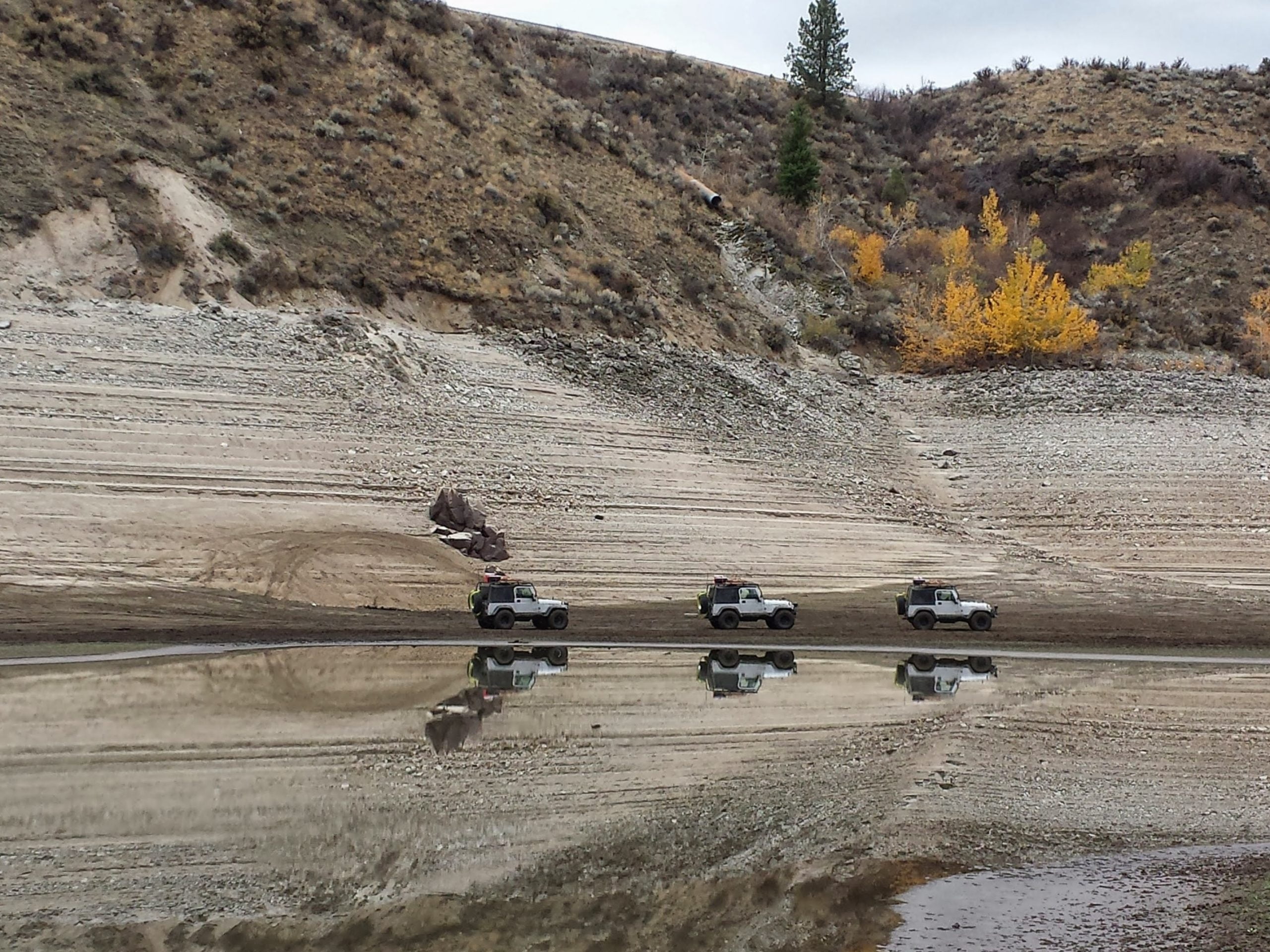 three jeeps reflected in water